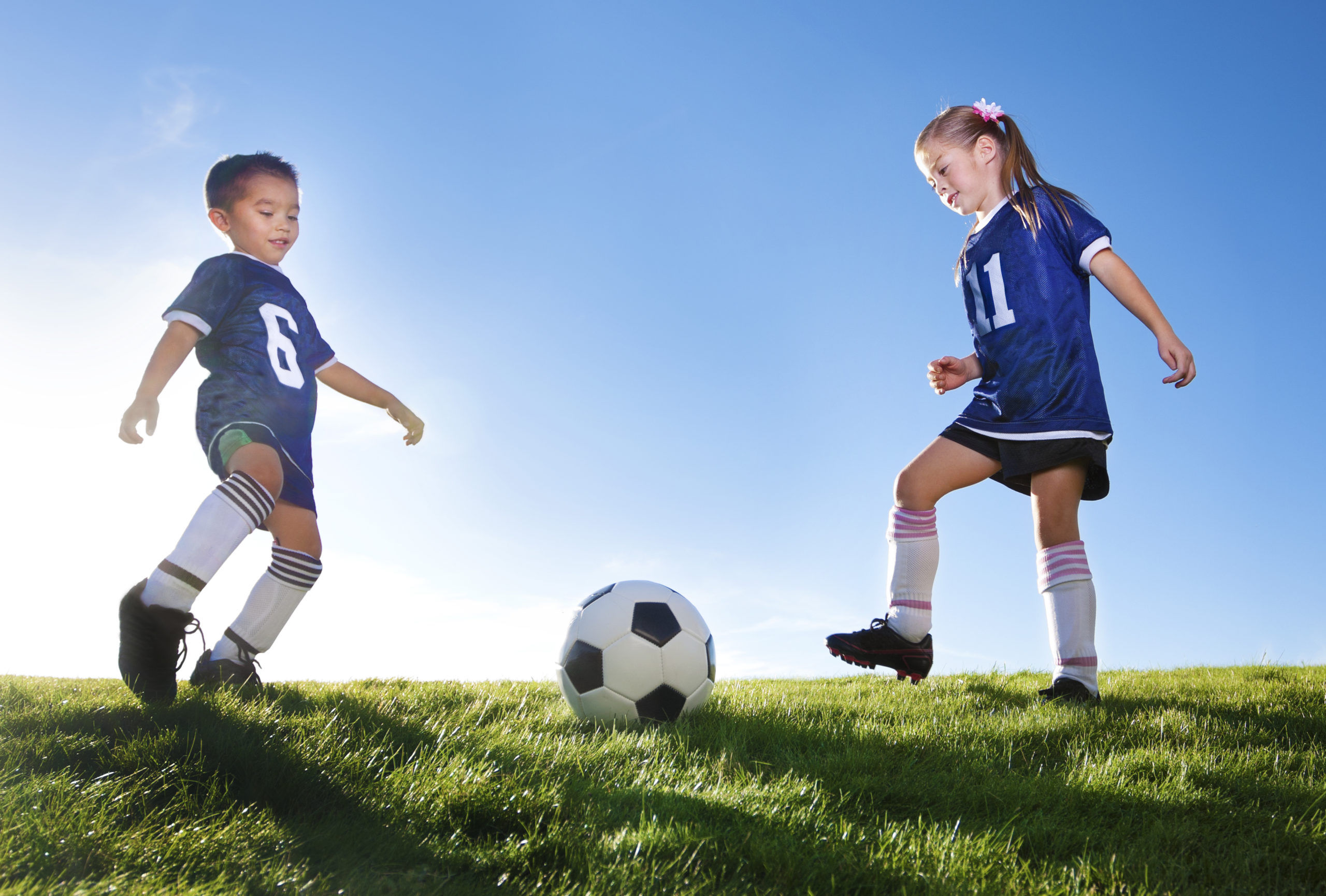 Young Soccer Players Kicking Ball Two Young soccer teammates kicking a ball